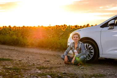 Woman waiting beside her car on a rural road