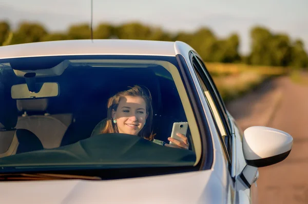 Tonårsflicka textning under körning vit bil — Stockfoto