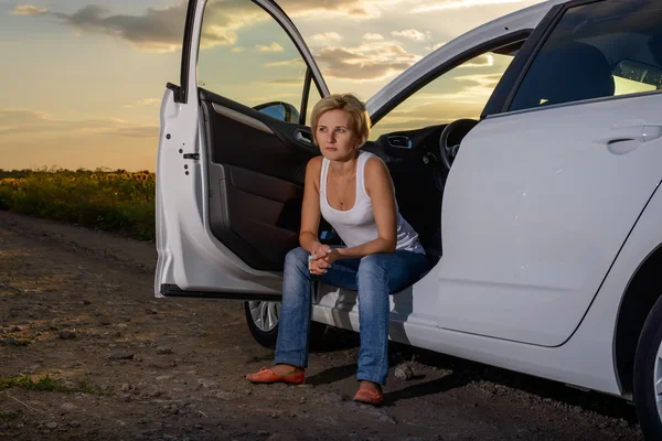 Улыбающаяся женщина, сидящая в открытой двери своей машины — стоковое фото