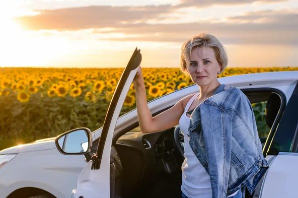 Donna attraente parcheggiata vicino a un campo di girasoli — Foto Stock