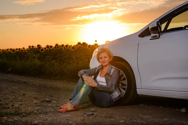 Woman waiting beside her car on a rural road — Stok fotoğraf