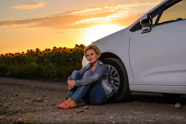 Woman waiting beside her car on a rural road — Stockfoto