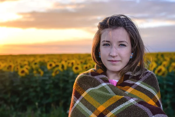 Девочка-подросток, завернутая в одеяло на подсолнечном поле — стоковое фото