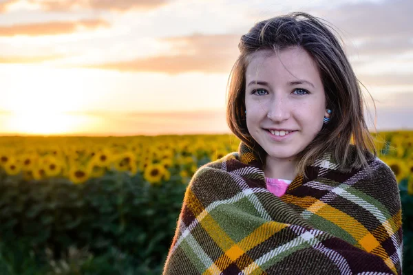 Девочка-подросток, завернутая в одеяло на подсолнечном поле — стоковое фото