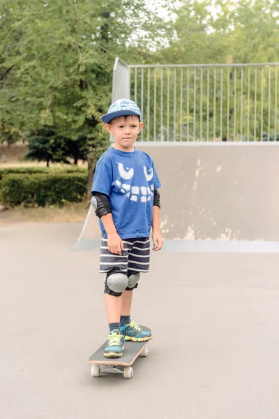 Mały chłopiec stojący na swojej deskorolce — Zdjęcie stockowe