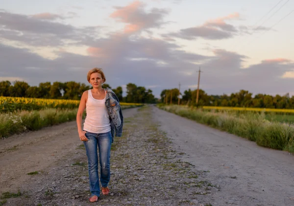 Aantrekkelijke blonde vrouw op een landelijke boerderij weg — Stockfoto