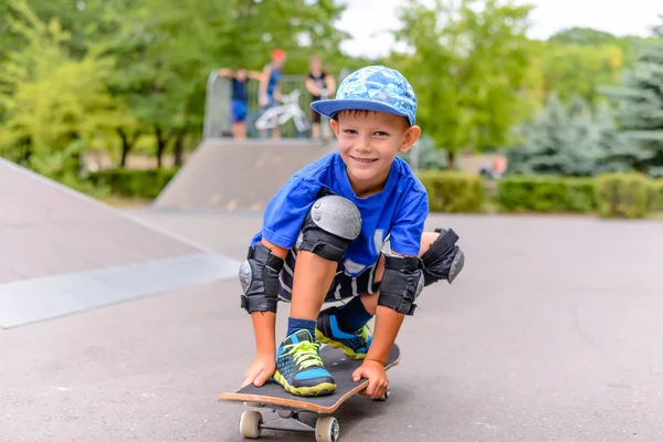 Kleine jongen op zijn skateboard grijnzend op de camera — Stockfoto