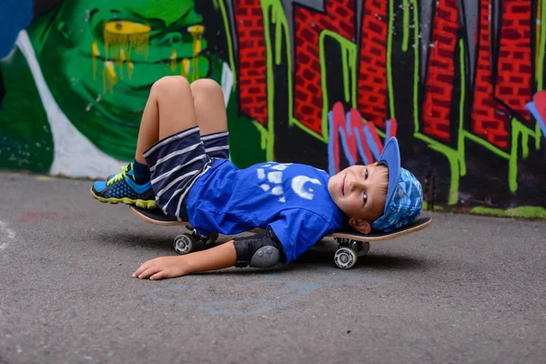 Impish joven niño relajándose en su monopatín — Foto de Stock