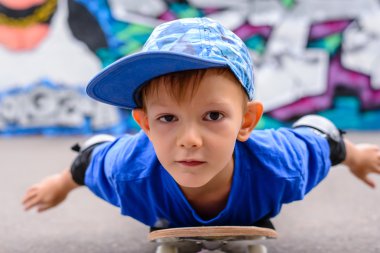 Small boy lying on his skateboard