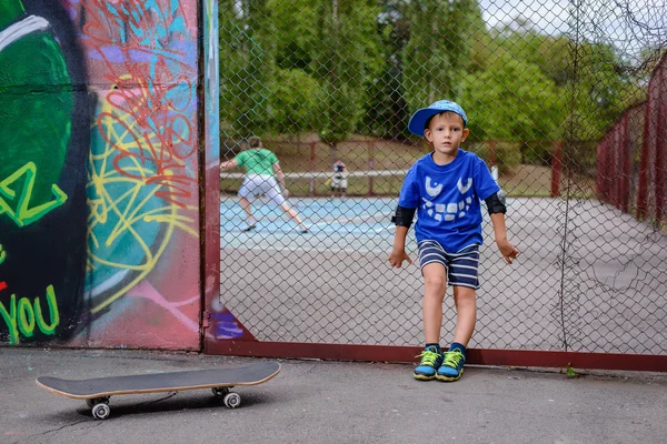 Niño con su monopatín en una pista de tenis —  Fotos de Stock