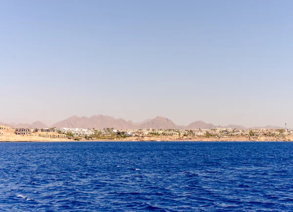 Distant sandy shore over blue water bay — Stockfoto