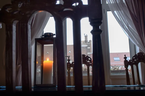 Lâmpada de close-up com vela acesa em pé sobre uma mesa de vidro contra a janela — Fotografia de Stock