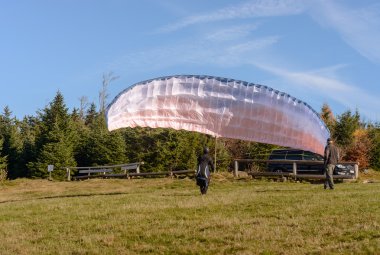 Yamaçparaşütü başlıyor. Paraşüt dağlar güneşli bir günde havayla doluyor.