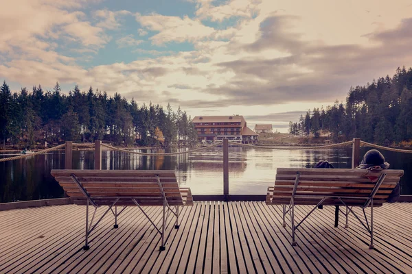 Вид с высоты на деревянный пирс и уютную скамейку на фоне красивого озера и леса в солнечный день. Панорамный вид на озеро. Германия. Европа . — стоковое фото