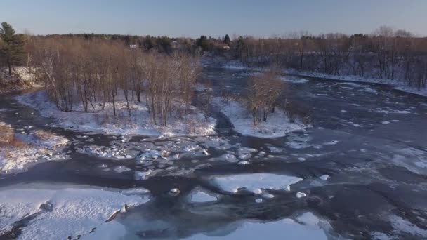 Vista aérea volando sobre el río congelado mostrando los rápidos y la nieve en las rocas. — Vídeo de stock