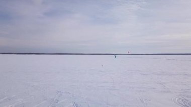 Buz balıkçısı kulübelerinin ve uçurtma sörfçülerinin kışın donmuş gölde görüntüsü.