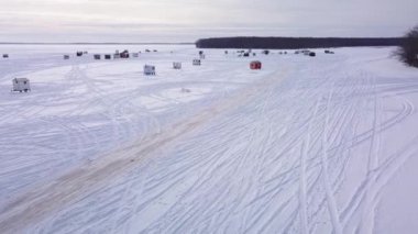 Donmuş gölün üzerindeki araba izlerinin üzerinden uçarak buz balıkçılarına doğru.