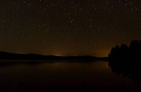 Sakin bir gölün üzerinde berrak bir gökyüzü olan güzel yıldızlı bir gece.