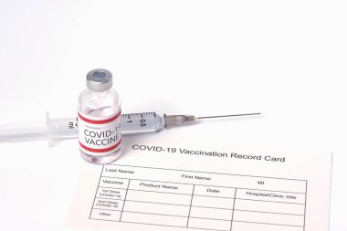 Beyaz arka planda Covid-19 ya da Coronavirus aşısı, şırınga iğnesi ve aşı sertifika kartı.