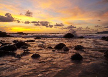 Güzel gün batımı turuncu gökyüzü ve deniz dalgaları Karon sahilinde kayalara çarpıyor, Phuket, Tayland