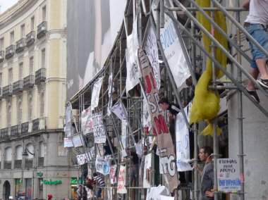Madrid, İspanya; 19 Mayıs 2011. 15-M protestoları sırasında afişler ve protestocularla (Indignados) dolu bir iskele. Fotoğraf 9 Mayıs 2011 'de Madrid, İspanya' da çekildi.