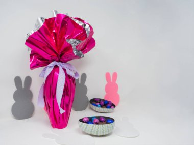 Mor kurdeleli dev Paskalya yumurtası, küçük çikolata yumurtaları ve diğer çikolatalar. Boş arkaplan