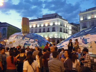 Madrid, İspanya; 29 Mayıs 2011. 15-M 'lik Indignados kampı sırasında Madrid' in Puerta del Sol istasyonunda protesto afişleriyle kaplanmış insanlar toplandı. Fotoğraf: 29 Mayıs 2011, Madrid, İspanya