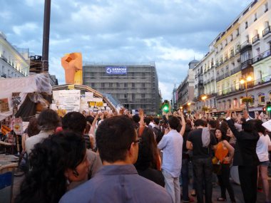 Madrid, İspanya; 29 Mayıs 2011. Madrid 'deki Puerta del Sol' daki 15-M hareket kampında düzenlenen mitingde insanlar alkış tutuyordu. Fotoğraf: 29 Mayıs 2011, Madrid, İspanya
