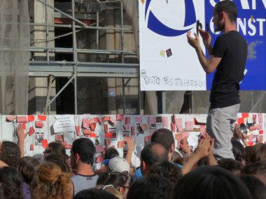 Madrid, İspanya; 11 Haziran 2011. Madrid 'deki Puerta del Sol' da düzenlenen protestolar sırasında inşaat bariyerine çarpan 15-M Indignados 'u alkışlayan genç adam. Fotoğraf 11 Haziran 2011 'de Madrid, İspanya' da çekildi.