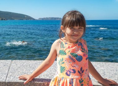 Güneşli bir yaz gününde Galiçya 'da, turuncu elbiseli ve at kuyruklu gülümseyen ilkokul kızı.