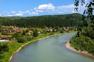 Ormanın ortasındaki dağ nehrinin tepesinden ve güneşli bir günde kıyıdaki köyden manzarayı seyret.
