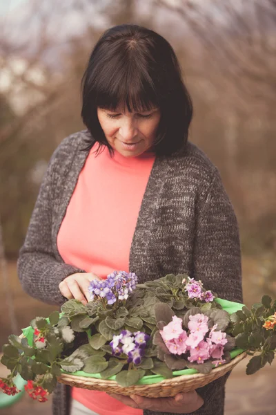 Mulher idosa com flores violetas — Fotografia de Stock