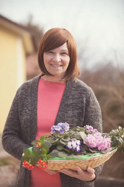 Elderly woman with violet flowers — Stock Photo, Image