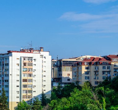 Balkonları ve mavi gökyüzü olan apartmanlar. Yeşillik. Parlak güneş ışığı
