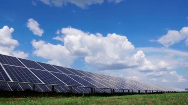 Açık havada yeni ekolojik güneş enerjisi inşaatı. Güneş panelleri çiftliği. Mavi gökyüzünün arka planında yeşil çimen üzerinde bulutlu paneller..