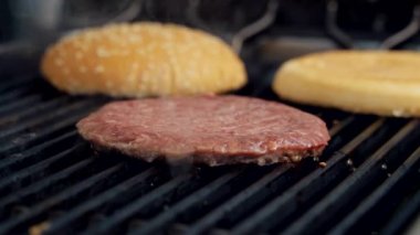 Et pirzolası ve ızgarada çörek pişirmek. Hamburger için leziz kızartma parçaları. Fast food restoranında sığır pirzolası kızartması. Yakın plan..