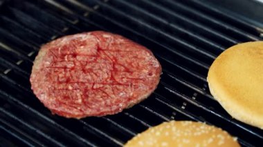 Izgarada fast food yemeği pişirmek. Et pirzolası ızgarada kızarıyor. Lokantada lezzetli bir burger hazırlıyorum. Yakın plan..