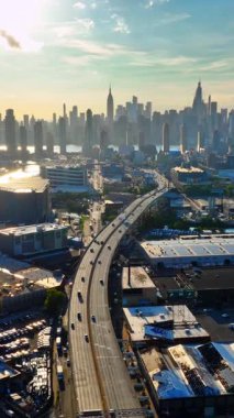 Ufuktaki Manhattan gökdelenleri ve endüstriyel önplanlı yükseltilmiş otoyolun havadan görüntüsü. Long Island Şehri. Dikey video.