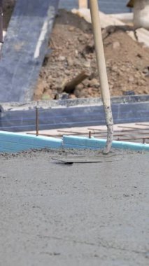 Beton yüzeye yakın çekim, uzun namlulu bir aletle dengeleniyor. Temeli tamamlama aşamasında. Dikey video.