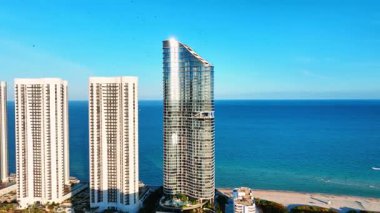 Miami 'deki Sunny Isles plajının ilk hattında lüks oteller. Şehrin ve okyanusun havadan görünüşü, insanlar dinleniyor..