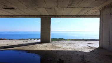 Sakin deniz manzaralı ve kubbe şeklinde yapıları olan açık beton bir bina. İnşaat alanının boş katı. Hava görünümü.