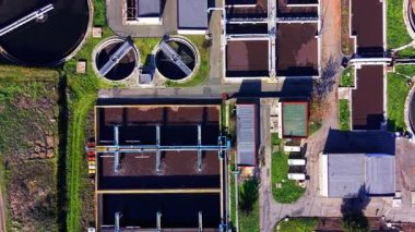 Altyapı ve yeşilliklerle çevrili çoklu tortu ve hava tankları olan atık su arıtma tesisi. Hava görünümü.