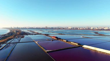 Hava aracı endüstriyel binalar ve şehir sınırının yanındaki pembe ve mavi tuz havuzlarının bir kısmını görüntüledi. Kentsel alana yakın renkli su.