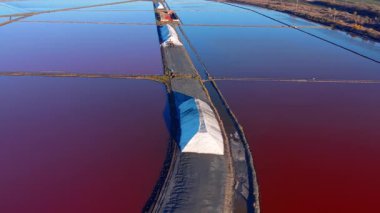 Dikdörtgen tuz havuzlarının yukarıdan aşağıya geniş bir hava manzarası. Su, toplanan tuzlu beyaz piramitlere sahip mikroorganizmalardan dolayı koyu pembe renktedir..