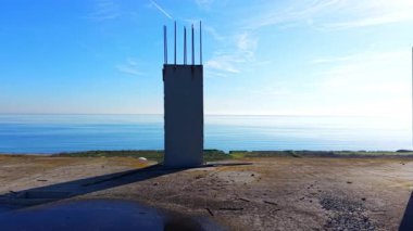 Dikey beton duvar ya da çelik demirli sütun. Düz beton bir çatıda. Arka planda deniz ve açık gökyüzü. Hava görünümü.
