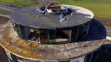 Yuvarlak beton bir yapının hava perspektifi. Açık alanda dairesel bir çatısı ve cam pencereleri hasarlı..