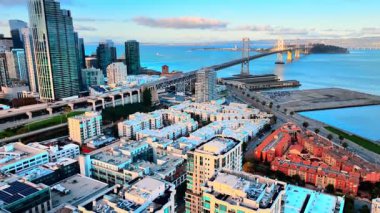 Güney Sahili San Francisco 'da Oakland Körfezi Köprüsü' nün arka planına uzanan bir yerleşim bölgesinin havadan görüntüsü. Apartman binaları, otoparklar ve sahil yolu..