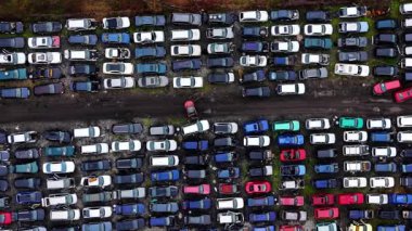 Eski, hasarlı ve çok renkli araçlar bir araba mezarlığı ve geri dönüşüm merkezinde dar sıralar halinde dizilmiş. Hurdalıkta kurtarılan arabaların yukarıdan aşağıya doğru görüntüsü.