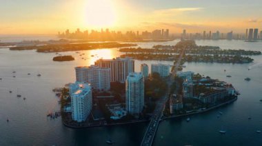 Altın saat boyunca denizle çevrili trafik geçiş adaları olan bir geçit manzarası. Köprü bağlantılı adaların havadan görüntüsü. Miami şehir merkezinde ufukta gökdelenler var..