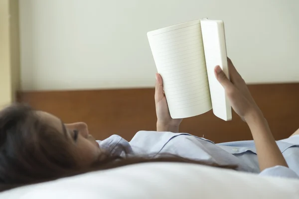 Jonge vrouw boek lezen liggend op het bed — Stockfoto